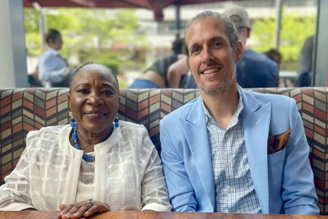 Two people sit side-by-side in a booth in a dining room