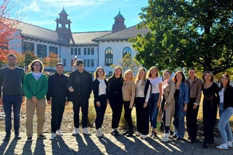 A group of people pose in a line outdoors in the fall