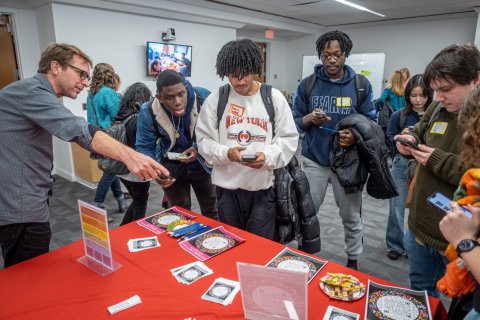 A group of college students stand at a table at a career fair and speak with a representative