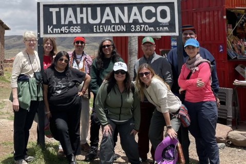 A group of people pose in front of a sign for Tiahuanaco