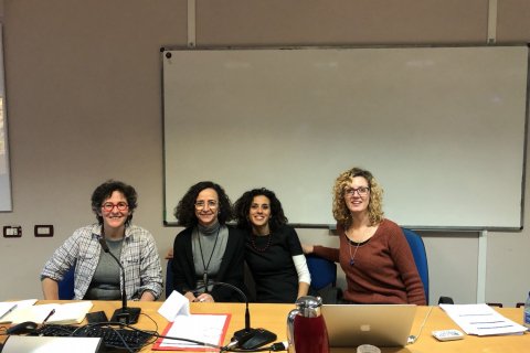 Four people pose at a presentation table, a blank whiteboard stands behind them