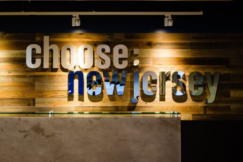 Metal wall sign for "Choose: New Jersey" fixed to a wooden wall fo