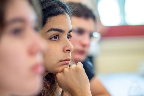 A close up of a seated student focusing on the professor 