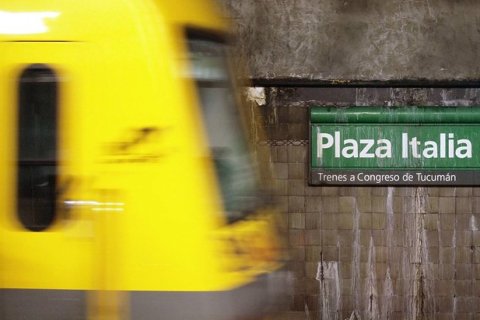 A yellow subway train moves through a station
