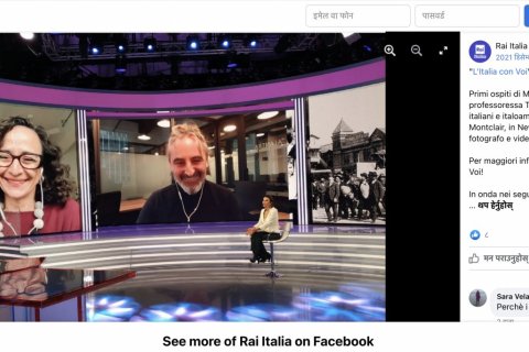A woman sits in a tv studio and speaks with interviewees on two large video boards