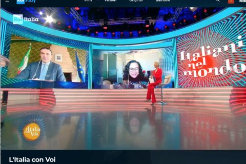Interior of a television studio with people sitting with large video boards in the background
