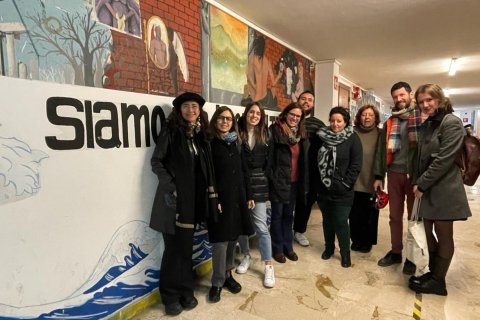 A group of people wearing winter coats pose in a building lobby