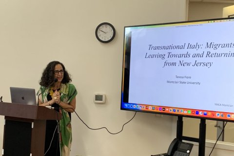 A woman stands at a podium and delivers a presentation