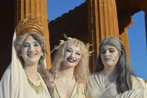 Three women dressed in classical-era Greek togas 