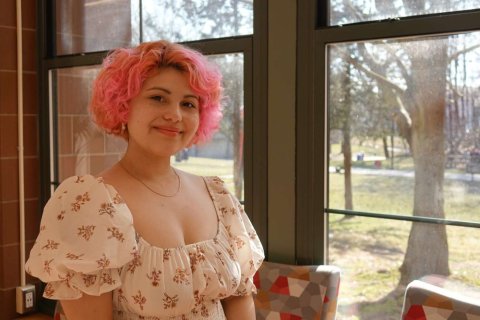A woman poses for a headshot by a sunny window