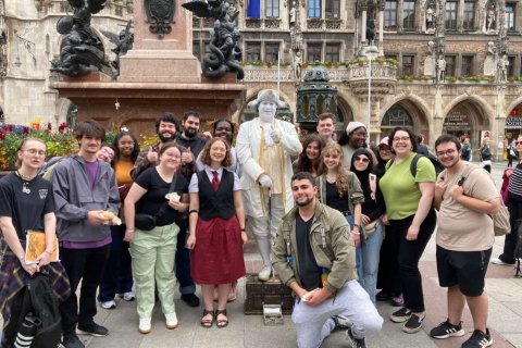 A group of college students pose with a human statue on the streets of Marienplatz in Munich