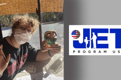 A woman wears a facemask and holds a painted carving  