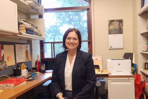 A woman poses at a desk in an office