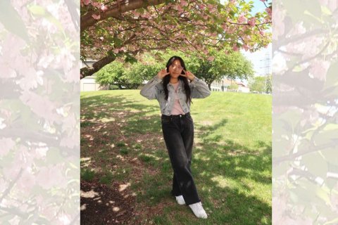 A woman poses beneath a cherry blossom tree.