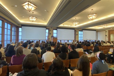 A large auditorium filled with people watching a presentation