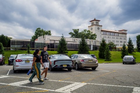 two students walking on a cross walk with a car in the background