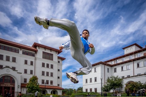Cameron Massay demonstrates a kick used in Taekwondo on a college campus.