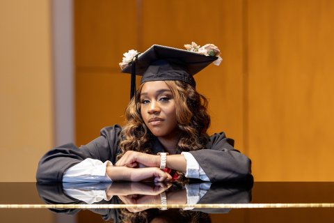 Lanaye Kemp with graduation cap and gown at piano
