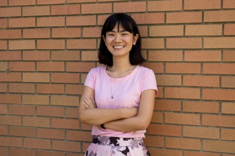 photo of professor Jennifer Yang standing smiling against brick wall