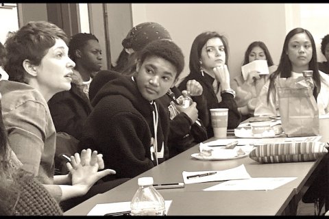 black and white photo of full classroom and students in discussion