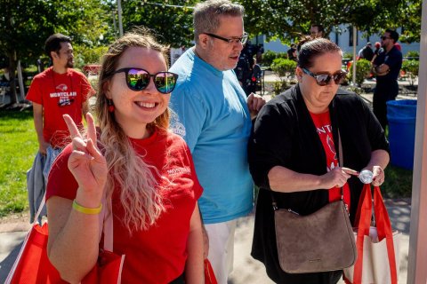 3 alumni, one giving a peace sign