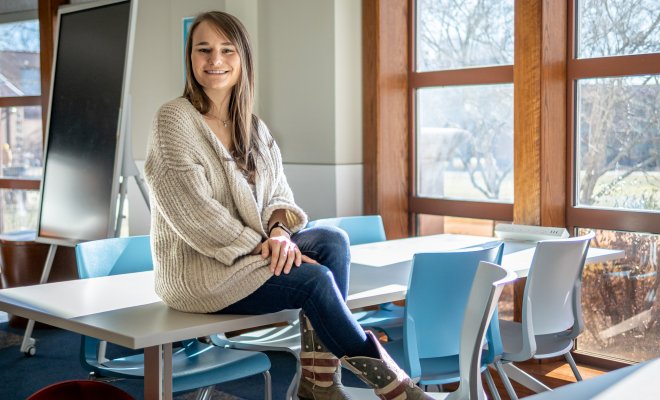 Alex Hatala sitting atop a classroom desk