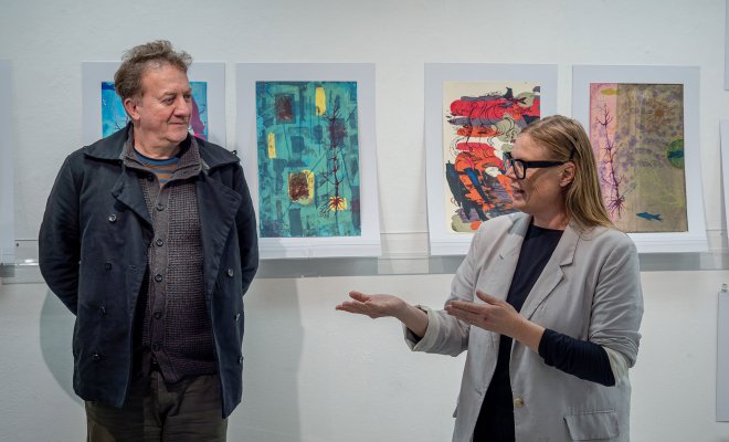 Thomas Mueller and Jennifer Wroblewsk stand before student artwork.