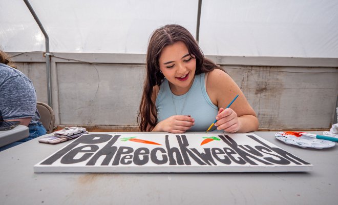 Female student paints sign.