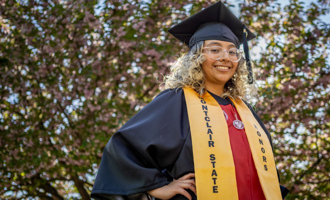 Student Mariana Luna-Martinez in graduation cap and gown with a gold honors stole.