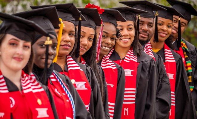 foreshortened view of a line of graduates in cap and gown with EOF shawl