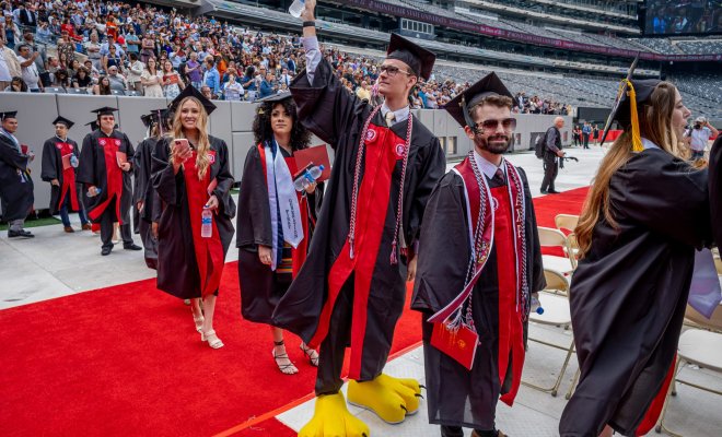 Kyle Cashin at commencement wearing graduation robe and Rocky's feet