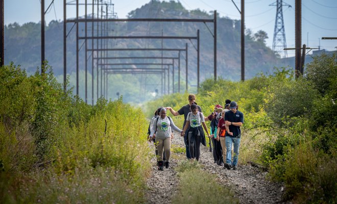 10 people walk on a trail that was once a rail road.