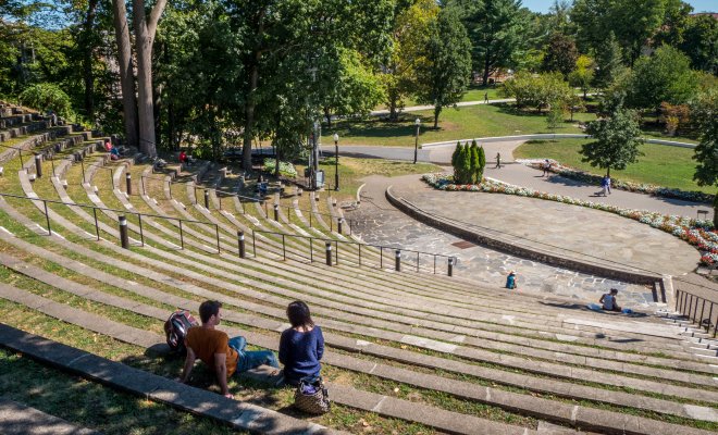 People sitting on tiered outdoor amphitheater seating on a campus