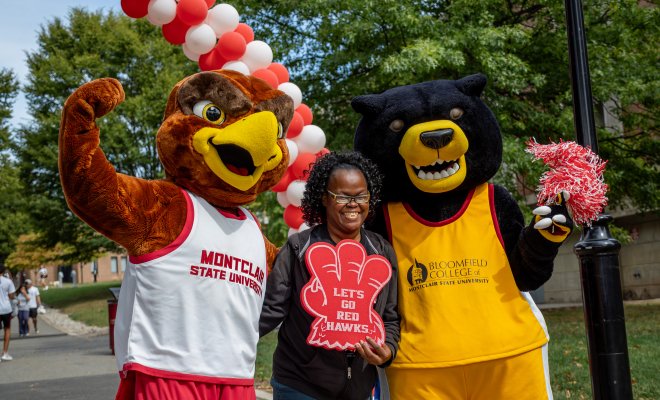 Montclair and Bloomfield mascots pose for a photo with a Homecoming attendee