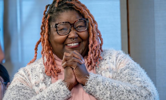 Khara Brown clasps her hands together in an expression of joy and gratitude.