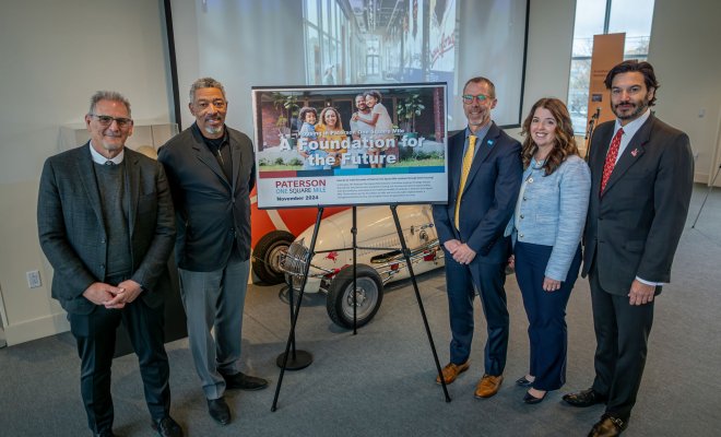Five people standing with sign in the center promoting One Square Mile initiative