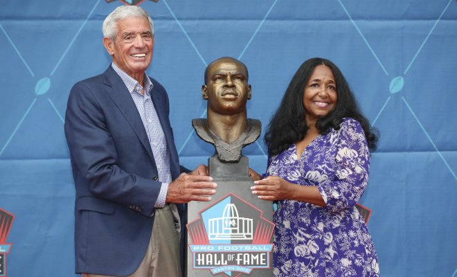 Melanie Mills and Jim Mora Sr. stand next to Sam Mills' head bust
