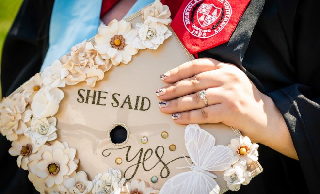 close up photo of a graduate's mortar boards with the words she said yes printed on it.