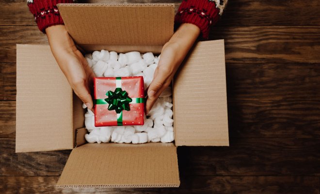 Small gift box being held over a slightly bigger box.