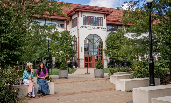 This picture shows two students sitting in front of a building at Montclair State University.