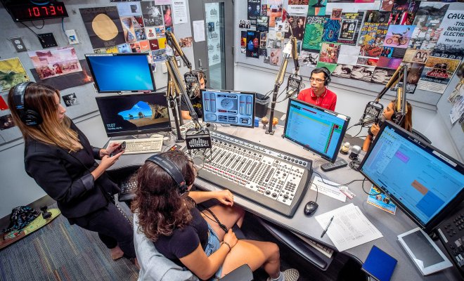 Students on air in broadcast studio.
