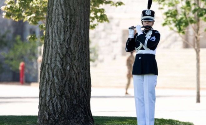 Ashley Mendeke playing flute in military uniform