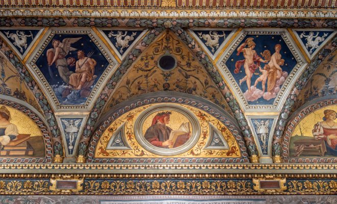 Bright restored Romanesque-style fresco on a ceiling cornice in a museum gallery, with gold colors and ornate details.
