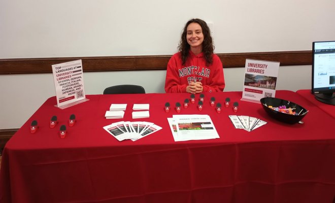 student sitting at table with red table cloth and giveaways
