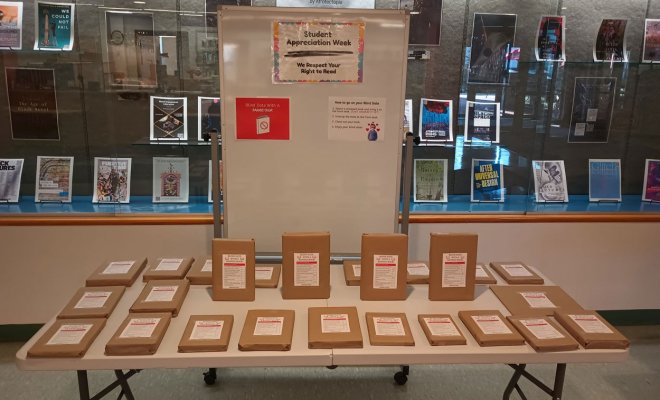 a display of many wrapped banned books and a whiteboard explaining it
