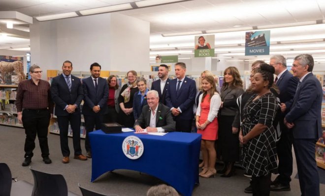 group surrounding governor phil murphy in a library