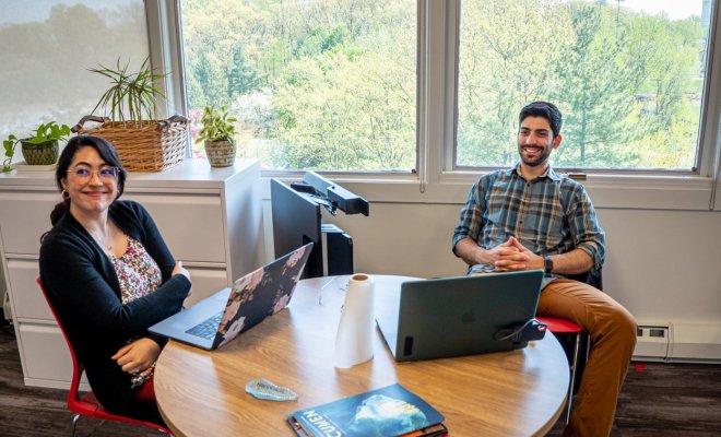 two staff members at a desk with laptops