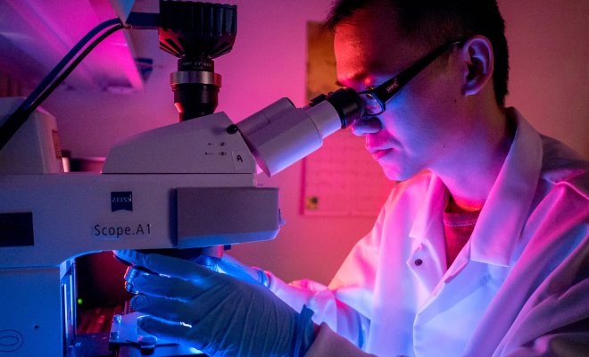 student in water testing lab using microscope