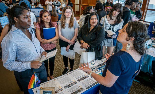 A recruiter speaks to a group of college students at a career fair