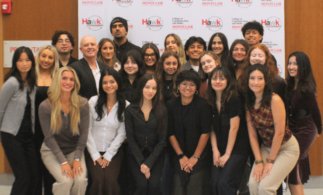 2025 cohort for Hawk Communications course posing in front of the CCOM step-and-repeat in the CCOM lobby.